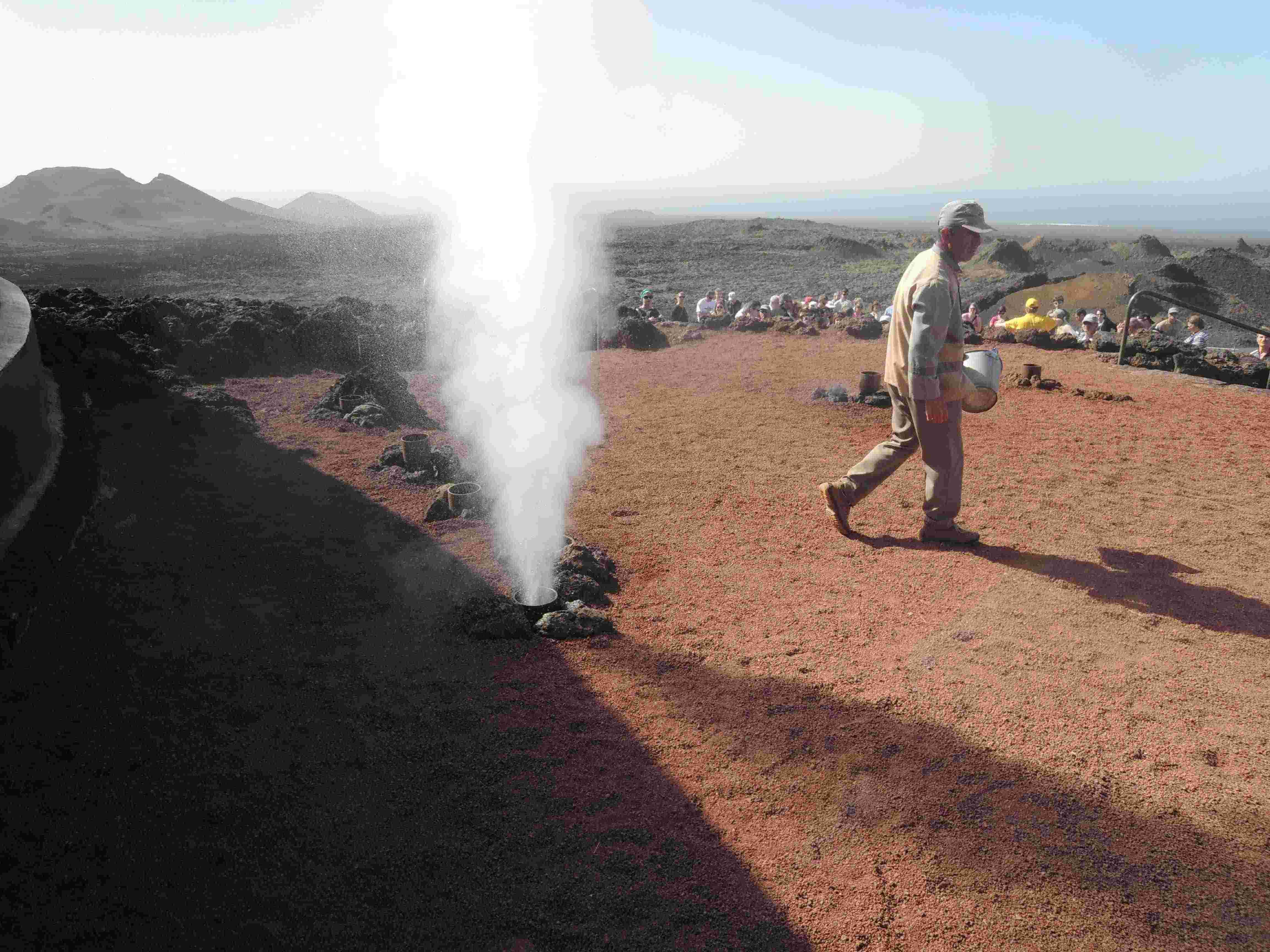 Tourists are shown how water poured into a hole close to hot lava will make a geyser